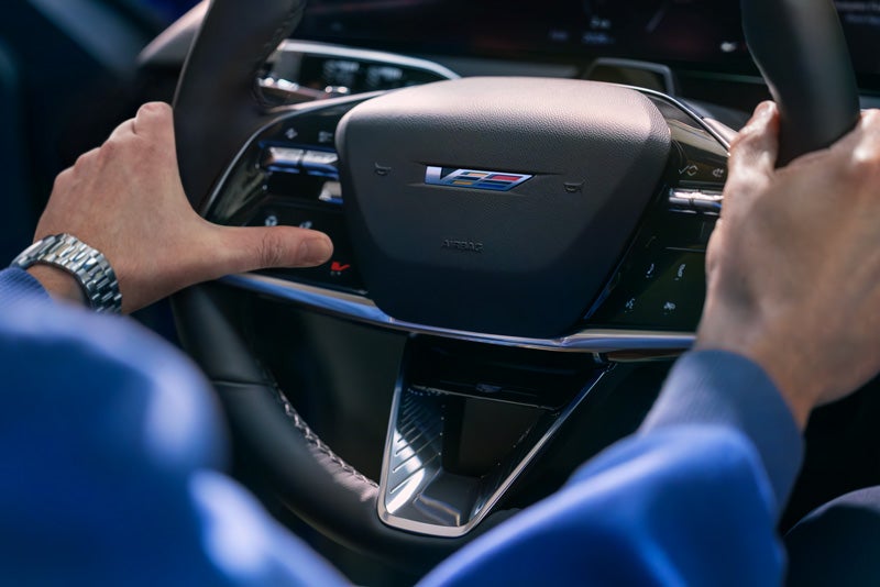 Close-up of a Man About to Press the V-Button on the 2026 OPTIQ-V Steering Wheel | Huston GMC in LAKE WALES FL