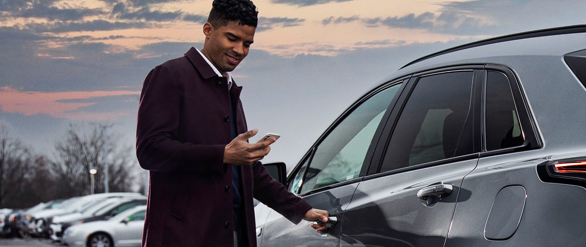 Man looking at phone next to a car