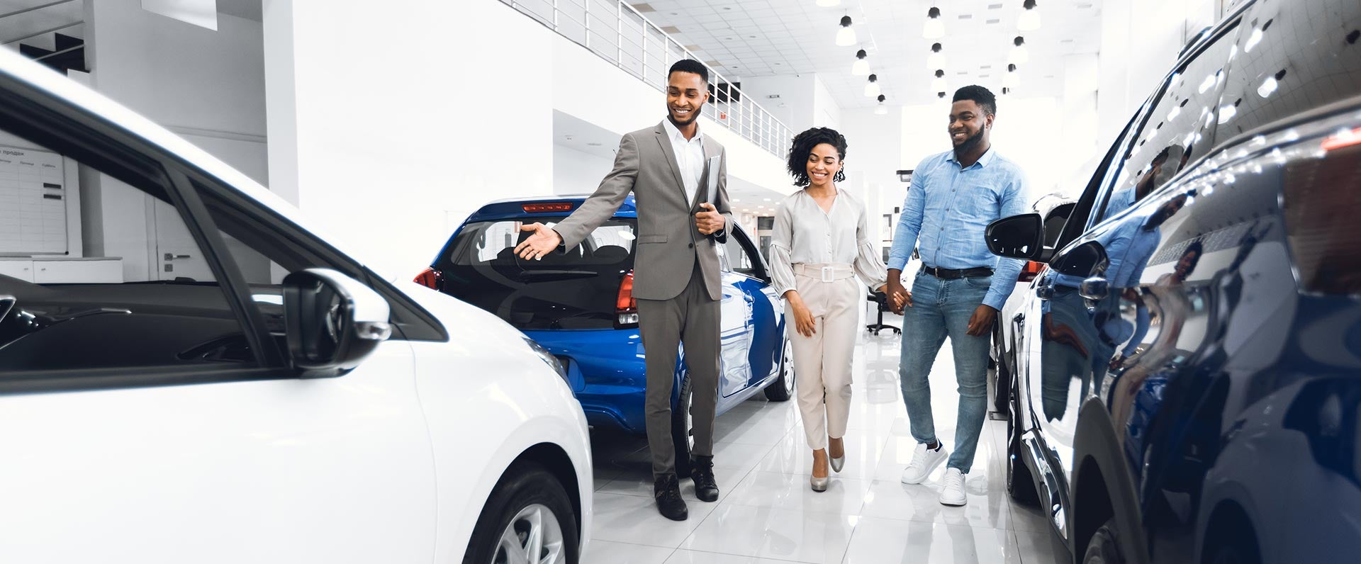 3 people walking through a car showroom